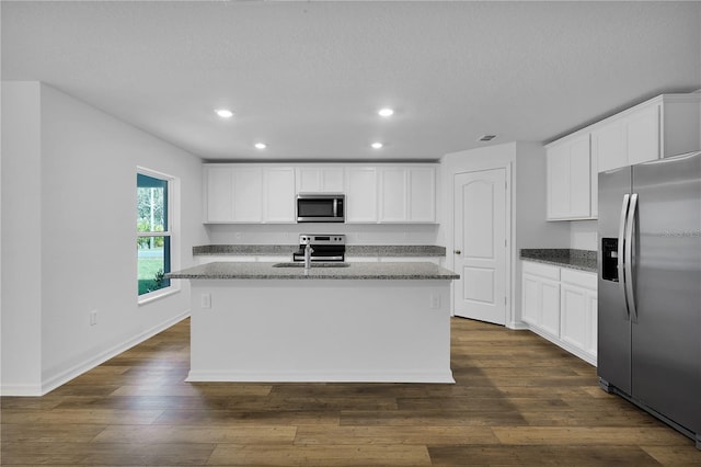 kitchen featuring white cabinets, appliances with stainless steel finishes, an island with sink, and dark wood-type flooring