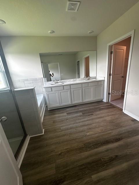 708 160th Ln E, Bradenton, FL 34212 - bathroom with wood finished floors, a garden tub, double vanity, and a shower with door