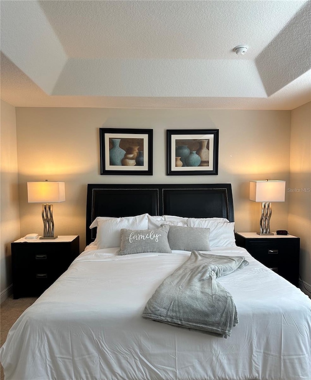 bedroom featuring a tray ceiling and carpet floors