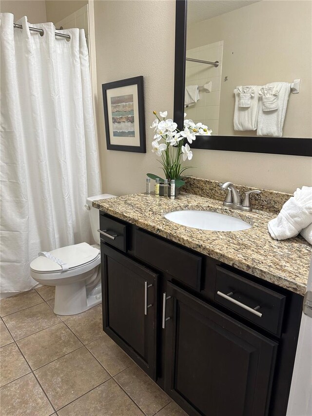 bathroom with a shower with shower curtain, tile patterned floors, vanity, and toilet