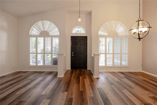 foyer with a wealth of natural light, baseboards, an inviting chandelier, and wood finished floors