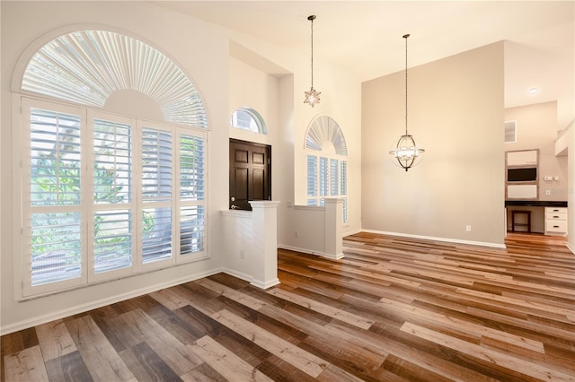 entrance foyer with wood finished floors, baseboards, visible vents, an inviting chandelier, and a high ceiling