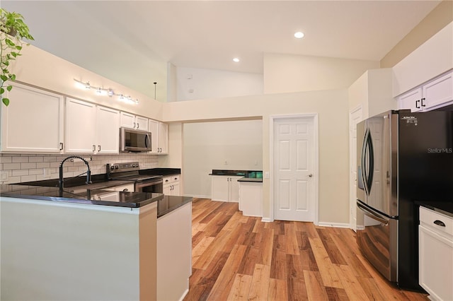 kitchen with light wood-type flooring, dark countertops, white cabinetry, stainless steel appliances, and decorative backsplash