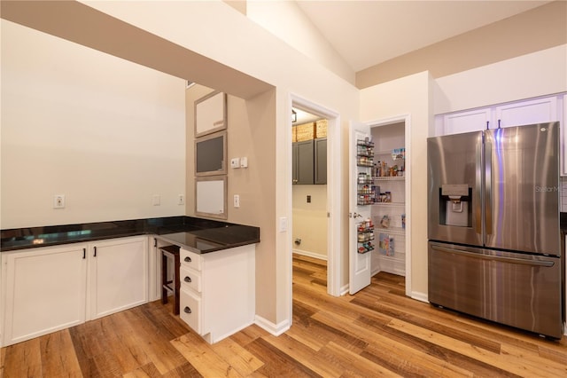 kitchen with dark countertops, white cabinets, light wood-style floors, and stainless steel refrigerator with ice dispenser