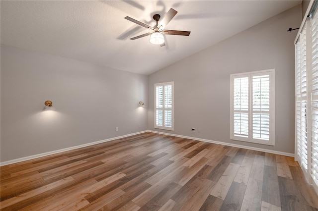 spare room featuring high vaulted ceiling, baseboards, a ceiling fan, and wood finished floors