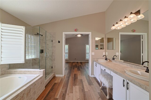 full bath featuring wood finished floors, lofted ceiling, a stall shower, a sink, and a bath