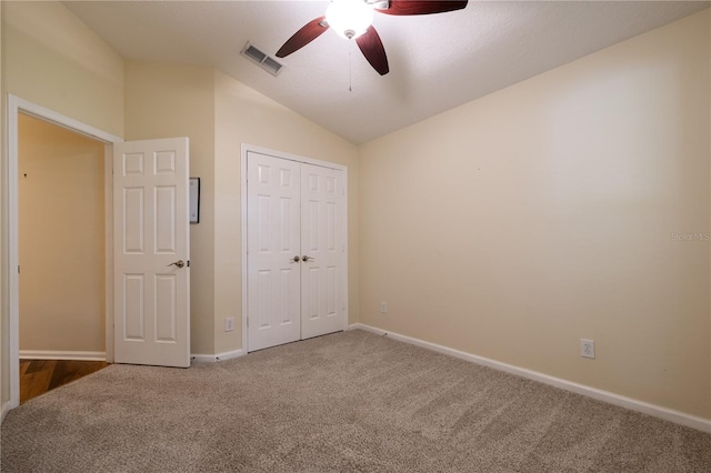 unfurnished bedroom featuring visible vents, a closet, carpet flooring, baseboards, and vaulted ceiling