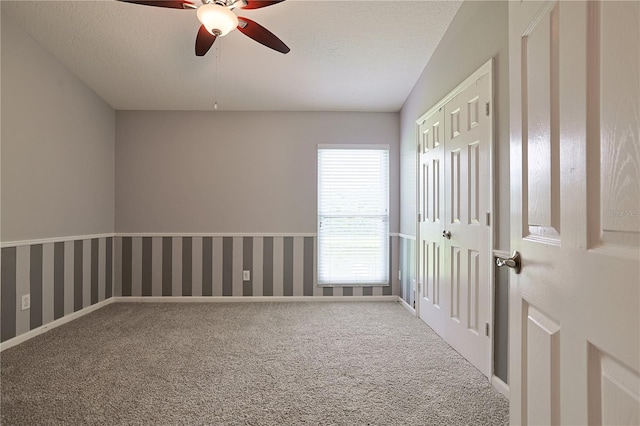 spare room featuring wallpapered walls, carpet flooring, baseboards, and a textured ceiling