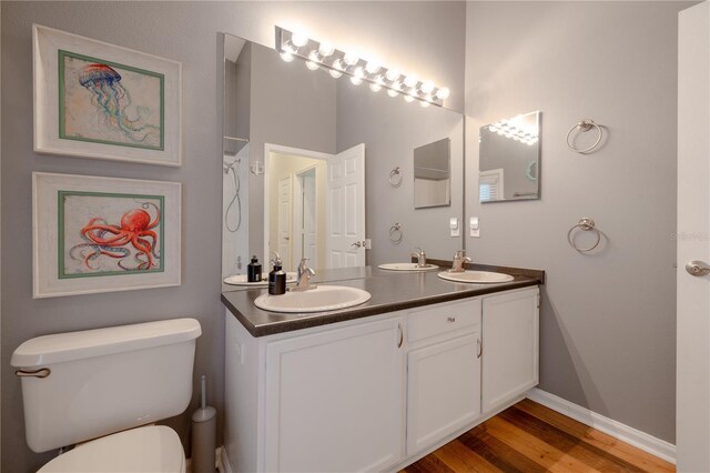 full bathroom featuring a sink, baseboards, toilet, and wood finished floors