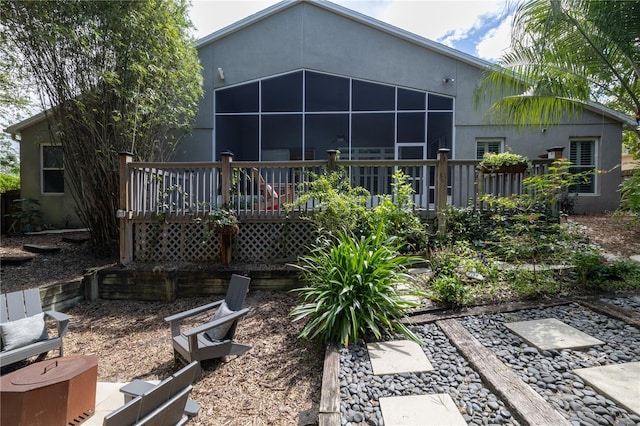 back of property featuring a wooden deck, a sunroom, and stucco siding