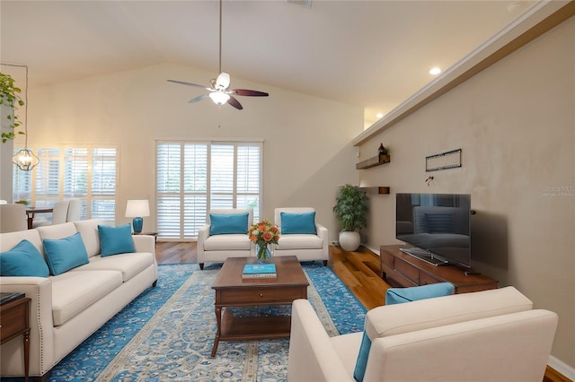 living room featuring ceiling fan with notable chandelier, lofted ceiling, and wood finished floors