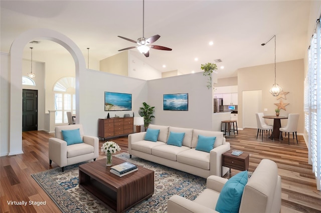 living area featuring visible vents, high vaulted ceiling, light wood-style flooring, recessed lighting, and arched walkways