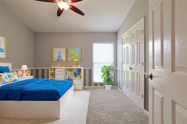 bedroom with a ceiling fan, a textured ceiling, and carpet flooring