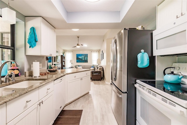 kitchen featuring white appliances, sink, ceiling fan, light wood-type flooring, and white cabinets