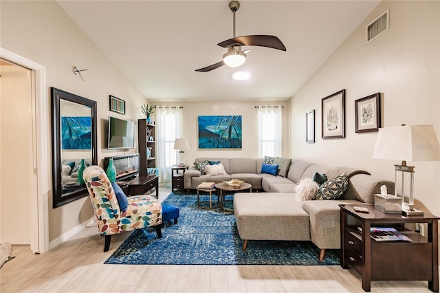 living room with light wood-type flooring, ceiling fan, and vaulted ceiling