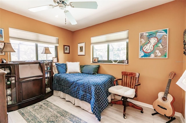 bedroom with ceiling fan, multiple windows, and light hardwood / wood-style floors