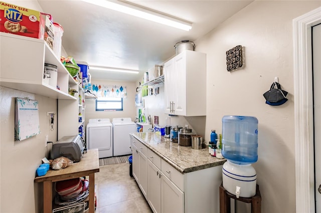 kitchen with white cabinets, light stone countertops, light tile patterned floors, and washing machine and clothes dryer