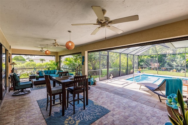 sunroom / solarium featuring a healthy amount of sunlight, ceiling fan, and a pool