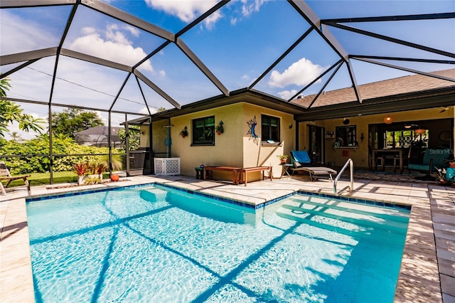 view of pool featuring glass enclosure, ceiling fan, and a patio