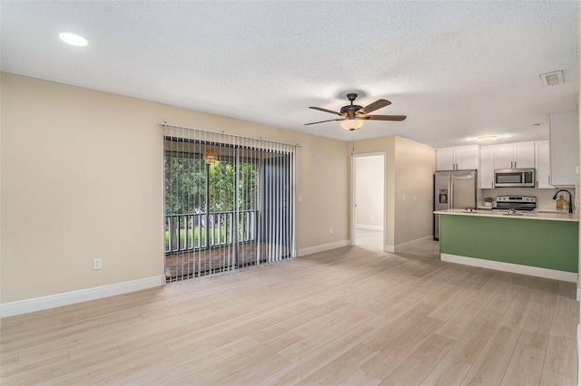 3822 Cortez Dr Unit D, Tampa, FL 33614 - unfurnished living room featuring a sink, light wood finished floors, ceiling fan, baseboards, and a textured ceiling
