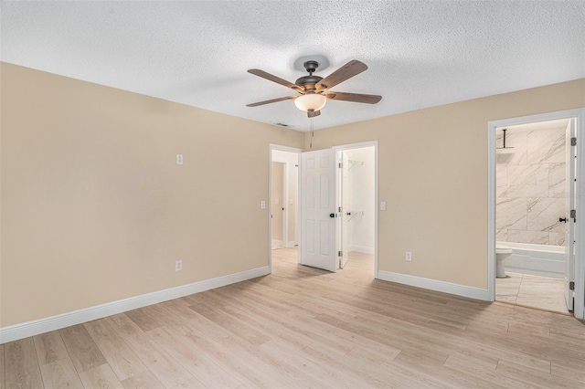 3822 Cortez Dr Unit D, Tampa, FL 33614 - unfurnished bedroom with light wood-style floors, a spacious closet, baseboards, ensuite bathroom, and a textured ceiling