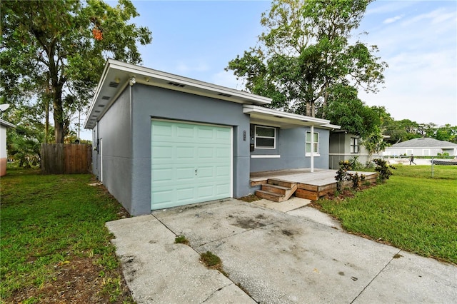 ranch-style house featuring an attached garage, fence, driveway, stucco siding, and a front lawn