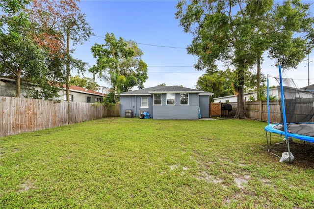 view of yard with central AC, a trampoline, and a fenced backyard