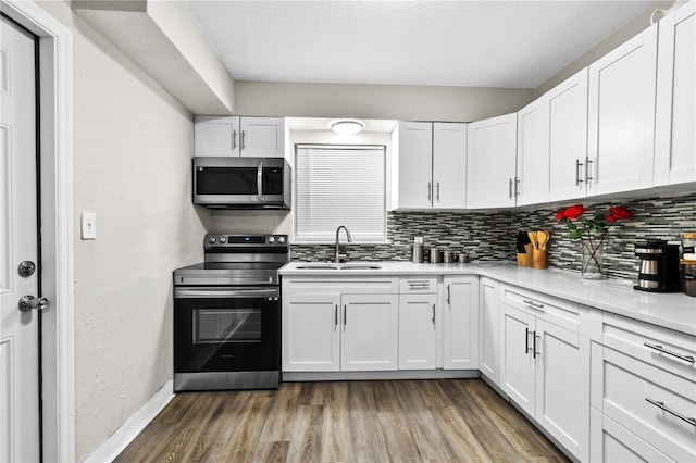 kitchen with dark hardwood / wood-style flooring, appliances with stainless steel finishes, sink, decorative backsplash, and white cabinetry