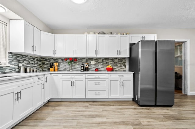 kitchen featuring light wood-type flooring, white cabinets, light countertops, and freestanding refrigerator