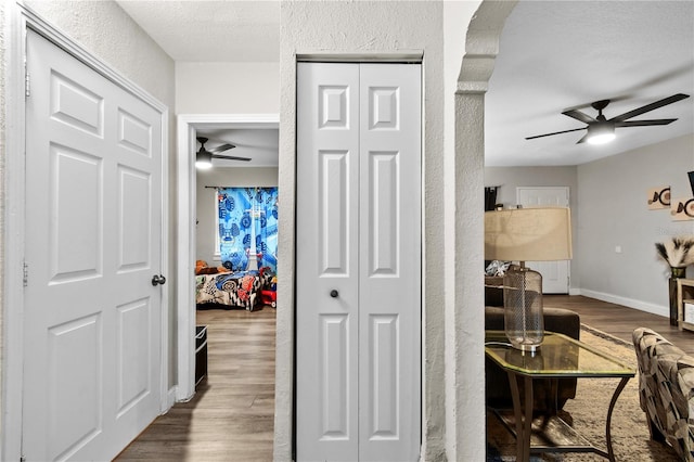 hall featuring dark wood-style floors, a textured wall, a textured ceiling, and baseboards