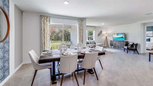 dining space featuring light tile patterned flooring and a textured ceiling