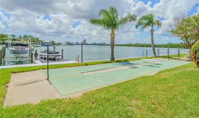 view of property's community with shuffleboard, a lawn, a boat dock, boat lift, and a water view