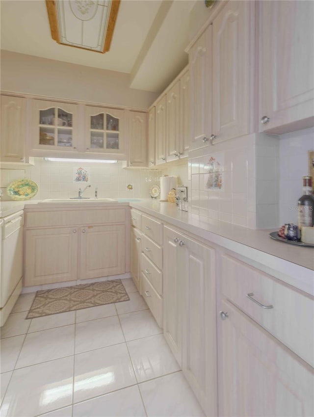 kitchen with decorative backsplash, dishwasher, light tile patterned floors, and sink