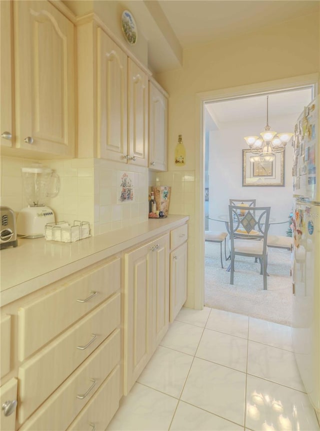 kitchen featuring hanging light fixtures, tasteful backsplash, light tile patterned floors, and a notable chandelier