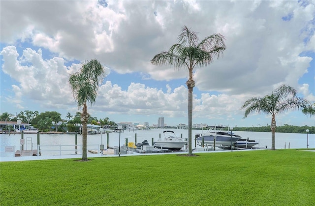 view of dock featuring a water view, boat lift, and a yard