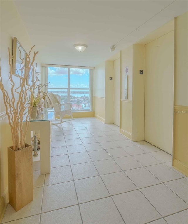 corridor featuring expansive windows, elevator, and light tile patterned floors