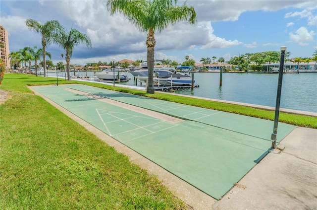 surrounding community with a water view, shuffleboard, a dock, and a yard