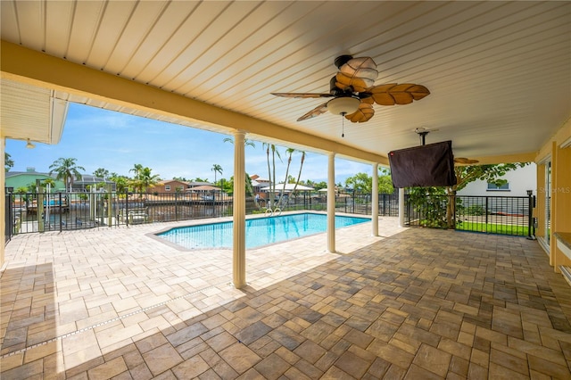 view of swimming pool with a patio, a water view, and ceiling fan