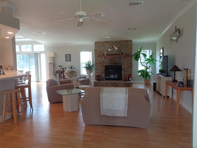 living room featuring ceiling fan, a fireplace, plenty of natural light, and light hardwood / wood-style floors