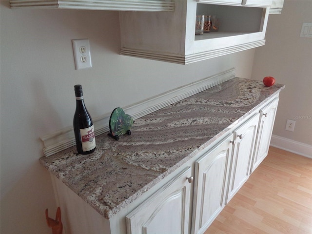 kitchen with light hardwood / wood-style flooring, light stone countertops, and white cabinets