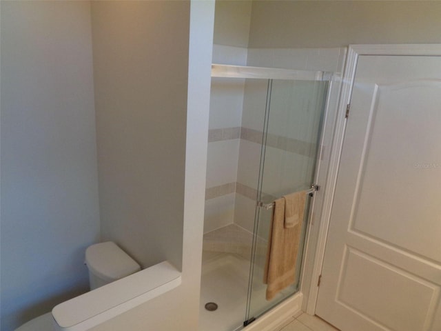 bathroom with toilet, walk in shower, and tile patterned floors