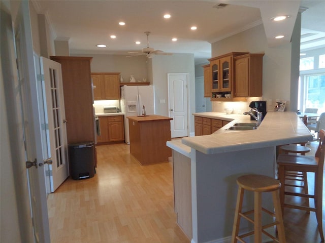 kitchen featuring sink, kitchen peninsula, ceiling fan, a kitchen bar, and a kitchen island