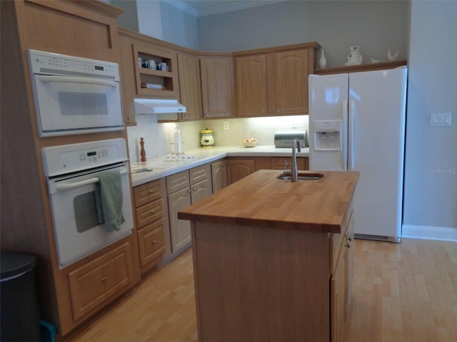 kitchen featuring white appliances, light hardwood / wood-style flooring, wood counters, tasteful backsplash, and an island with sink