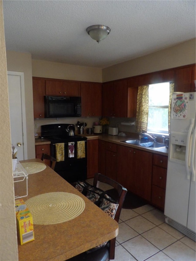 kitchen featuring black appliances, light tile patterned floors, light countertops, and a sink