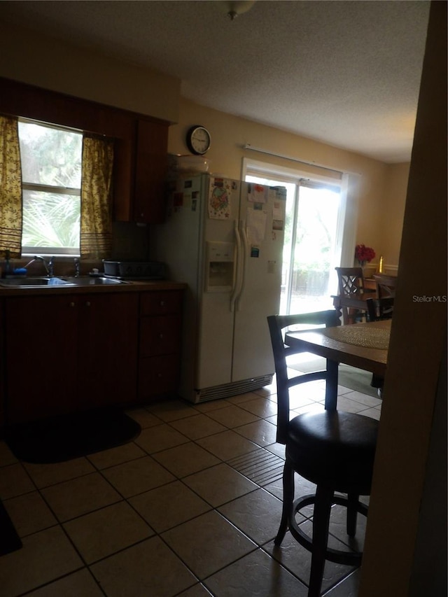 kitchen with tile patterned flooring, white fridge with ice dispenser, and a sink