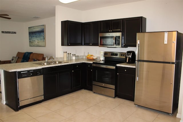 kitchen featuring sink, kitchen peninsula, stainless steel appliances, light tile patterned floors, and ceiling fan