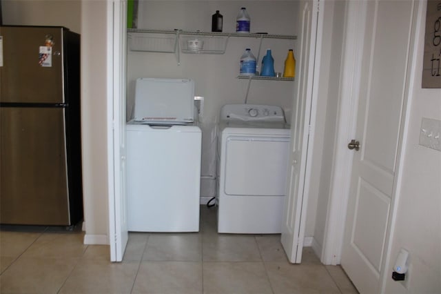 clothes washing area with washing machine and dryer and light tile patterned floors