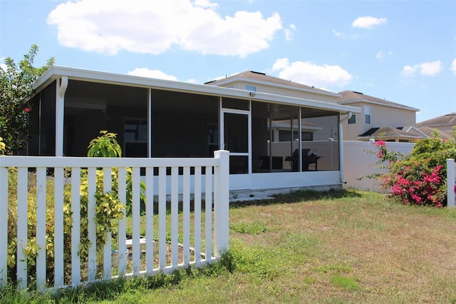 back of property with a sunroom and a yard