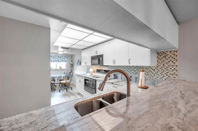 kitchen featuring light hardwood / wood-style floors, electric range, sink, white cabinets, and backsplash