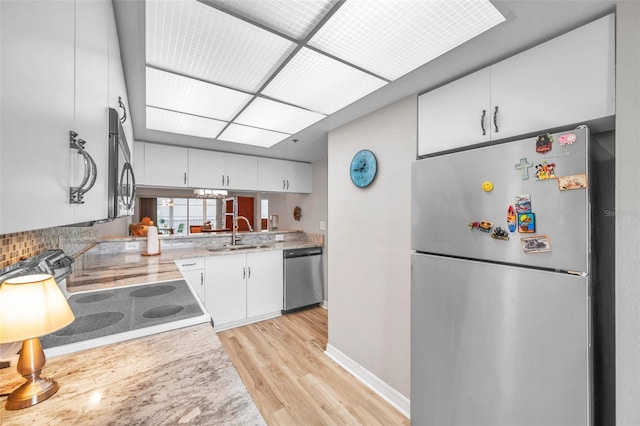 kitchen with white cabinets, stainless steel appliances, sink, and light hardwood / wood-style flooring